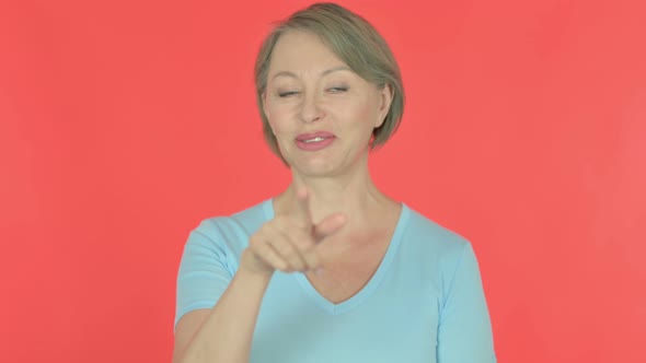 Old Woman Pointing at the Camera on Red Background