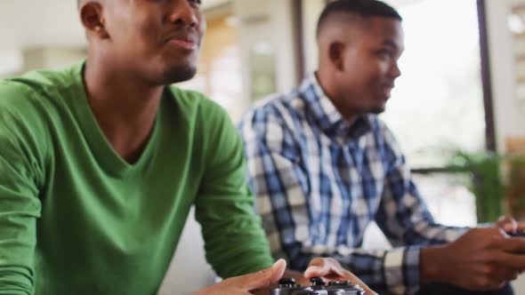 Two african american brothers sitting on a couch and playing video games