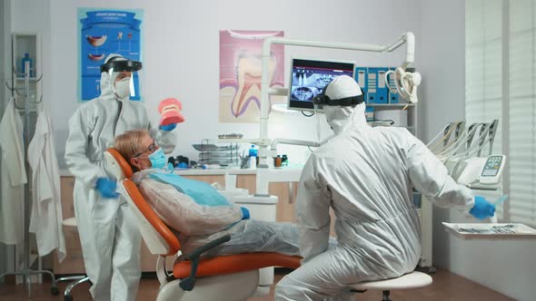 Dentist in Coverall Explaining Dental Hygiene Using Dental Skeleton