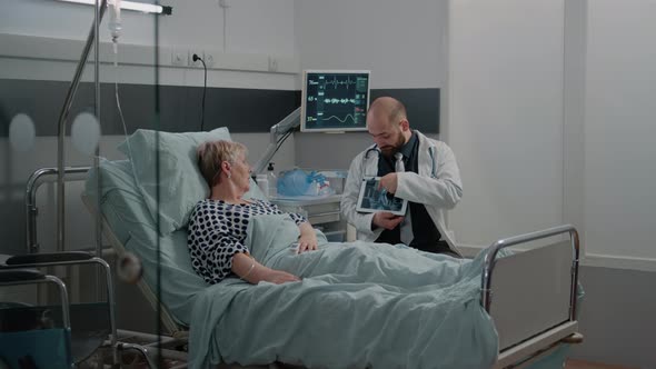 Doctor Explaining x Ray Scan Results on Tablet to Aged Patient