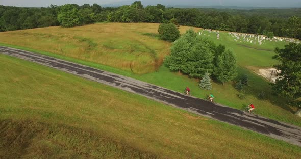 Aerial views of family bicycling along pastoral country roads.