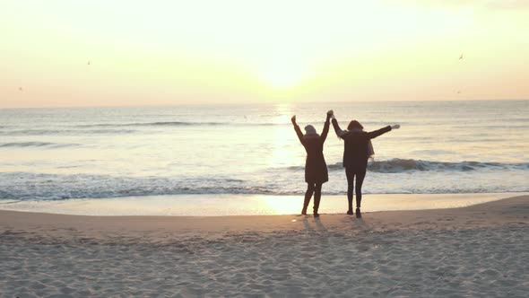 Two Beautiful Girls Have a Good Time at Sea at Sunrise or Sunset