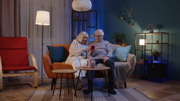 Grandfather and Grandmother Talking Making Online Shopping on Mobile Phone Sitting at Home Sofa