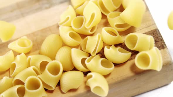 Raw pasta falling on chopping board