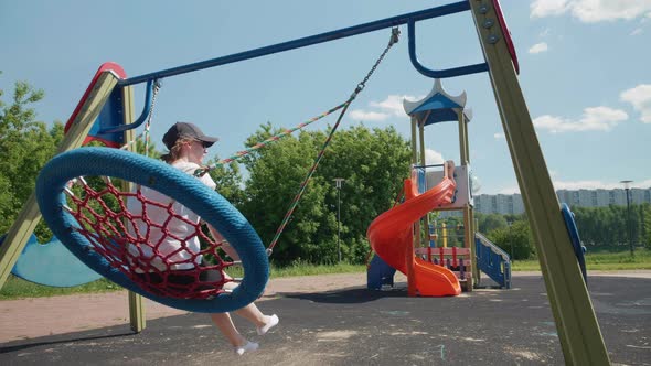 Slow Motion of Young Caucasian Woman Swinging on Big Blue Wicker Nest Swing