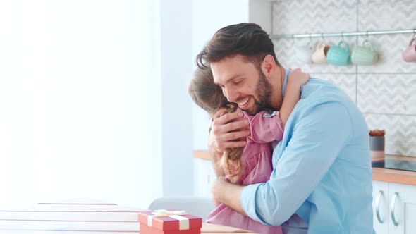 Embracing young father and little girl in home interior