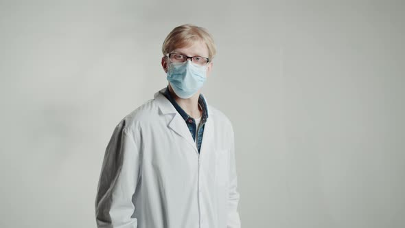 Caucasian Man Doctor in Medical Mask in Glasses Showing Red Pills Looking in Camera on White