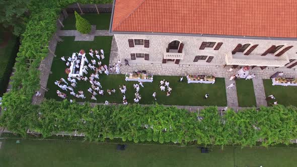 People in White Suits Walk Between the Laid Tables in the Courtyard of Villa Milocer