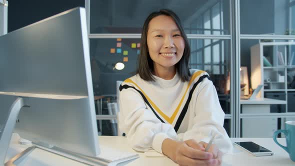 Portrait of Attractive Asian Girl Smiling Looking at Camera in Workplace in the Evening