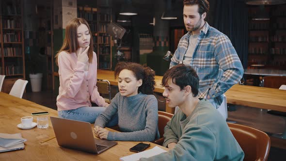 Thoughtful Millennial People Group Look on Laptop Screen at Library