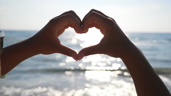 Woman Making Heart Through Her Hands with Seascape at Background