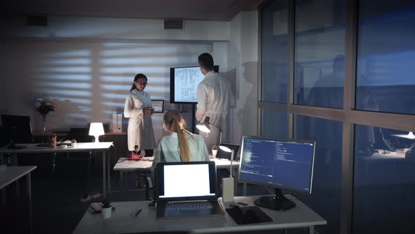 Group of Multiracial Electronics Development Engineers Discussing Something on a Big TV Screen in