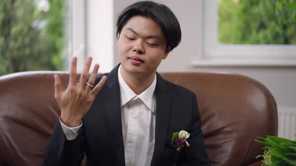 Happy Newlywed Asian Man Showing Finger with Ring Smiling Looking at Camera