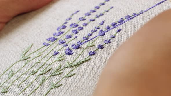 Woman makes embroidery a beautiful picture of lavender flowers. Handmade craft embroidery.