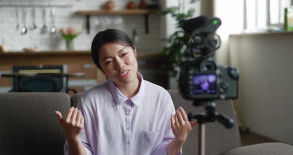 Young and Attractive Asian Woman Recording Video Blog with Professional Video Camera Mounted on