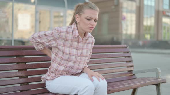 Young Woman Having Back Pain While Sitting on Bench Outdoor