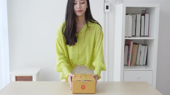 Young asian woman walking and holding cardboard box at home.