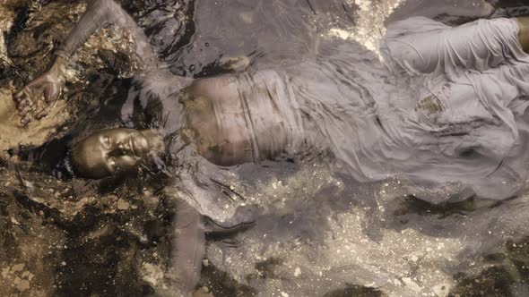 A Woman Submerged in Water Covered All Over with Gold Paint
