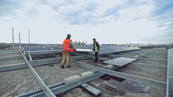 Technicians installing solar panel on metal base
