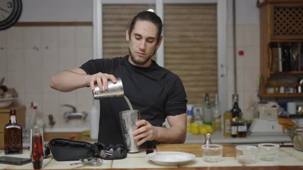 Handsome Barman Mixing Lime Juice with Alcohol in a Cocktail Shaker and Closing It to Shake It