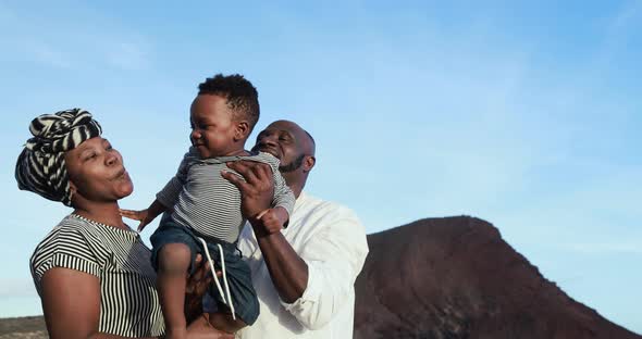 Cheerful african parents having fun with little son on the beach outdoor - Family and love concept