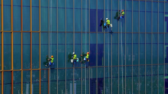 Five Workers in Protective Covid Masks and Blue and Yellow Work Clothes are Washing the Outside