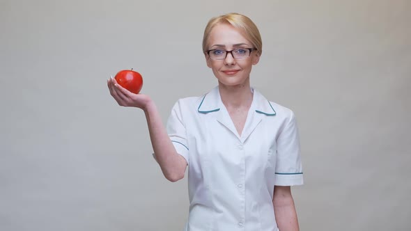 Nutritionist Doctor Healthy Lifestyle Concept - Holding Organic Red Apple and Jar of Vitamin Pills