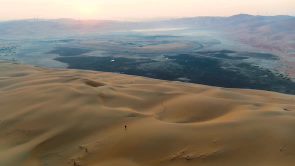 Aerial view of a man walking alone in the top of dunes, U.A.E.