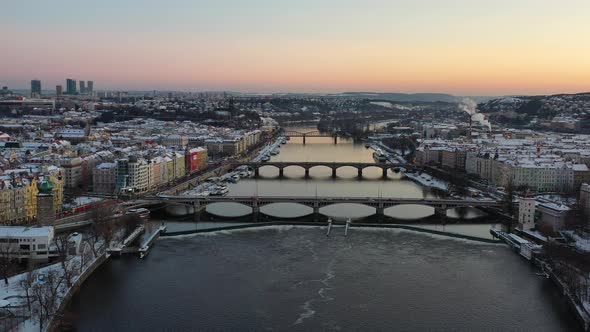 Prague Czech Republic at cold winter evening, aerial view, bridges above Vltava river, snow capped b