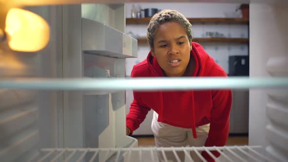 Disappointed African Woman Looking Inside Empty Refrigerator