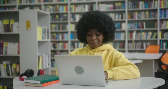 Focused African American Woman Studies on Laptop in Library