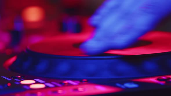 Closeup of DJ hands mixing and scratching music on vinyl plate. DJ mixes music using mixing console