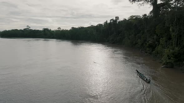 Aerial sunny day shot of beautiful boat sailing in the river with surrounded forest .