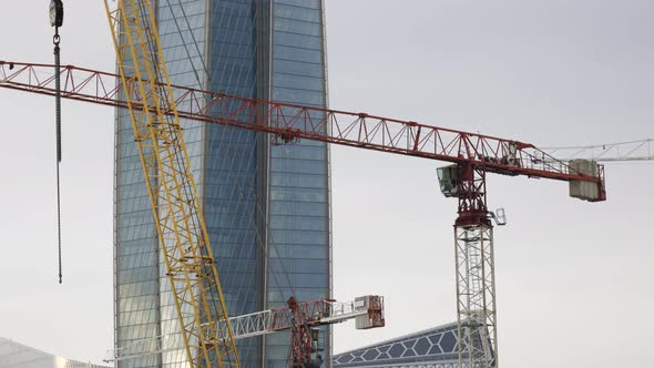 High crane works on a construction site with a glass building tower