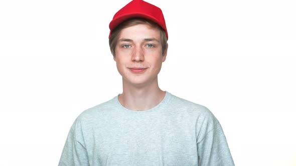 Portrait of Positive Hipster Teenager Wearing Red Cap and Grey Tshirt Smiling Showing Thumb Up Being