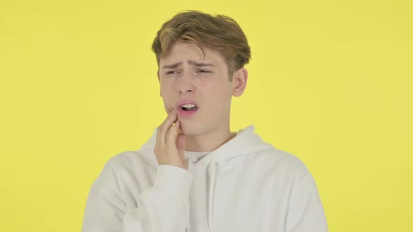 Young Man Having Toothache on Yellow Background