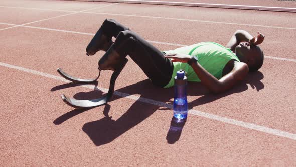 Disabled mixed race man with prosthetic legs lying on race track
