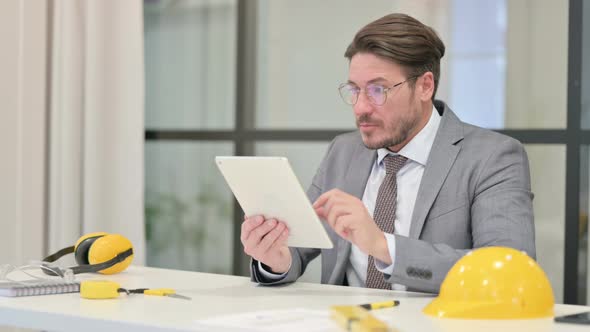 Middle Aged Engineer Celebrating Success on Tablet in Office