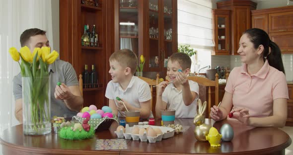 a Happy Family Sits at a Table and Paints Easter Eggs