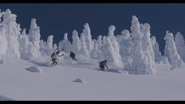 Snowboarders And Skier Traversing Fresh Powder