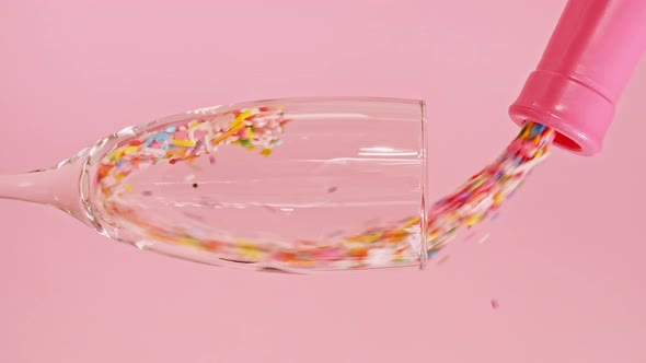 Colorful Candy Confectionery Run Poured Into a Wineglass Glass on Pink Background