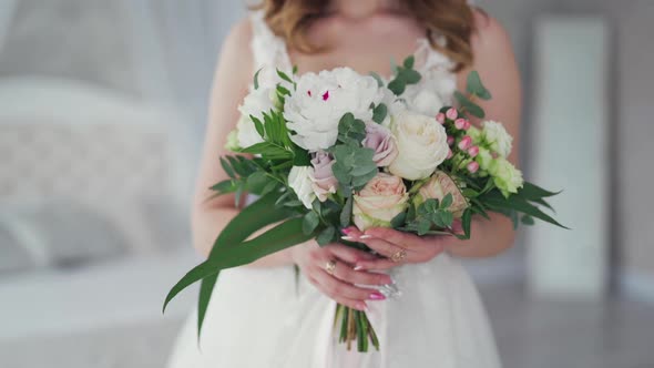 Wedding bouquet of creamy roses in the hands of a beautiful bride.