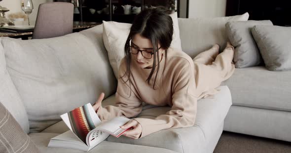 Peaceful Millennial Woman Relaxing Seated on Comfortable Cozy Reading a Book