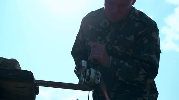 Close View Handyman Cuts Metal Detail with Saw Against Sky