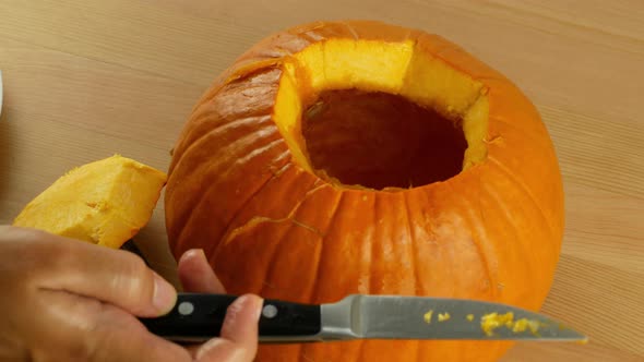 Woman cleaning a pumpkin preparing her for the holiday of Halloween. Close-up of an orange pumpkin.