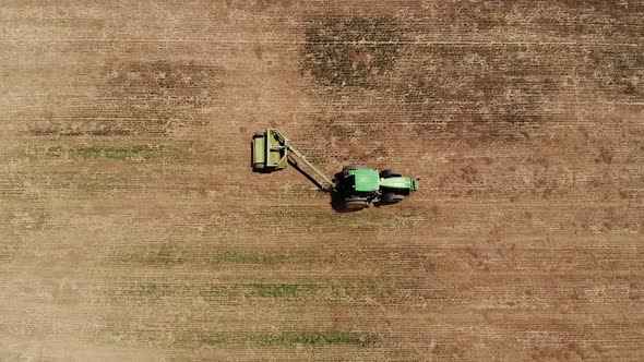 Aerial View of a Tractor with a Mower Mows the Grass on an Empty Field. Field Preparation and