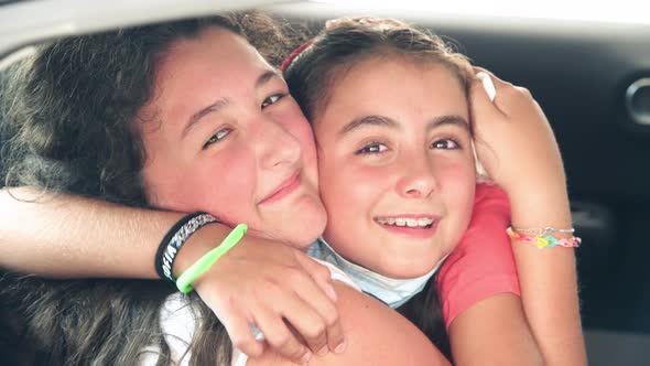 Two Young Girls Embracing in the Car at Drivethru After Negative Covid Swab Test