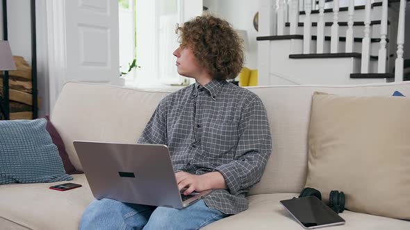 Man Sitting on the Couch in the Living-Room and Working on Laptop