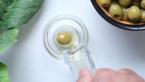 Bottle of Olive Oil and Fresh Olive in a Container on White Background