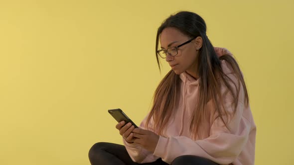 Close-up of Black Woman in Eyeglasses Working on Smartphone.